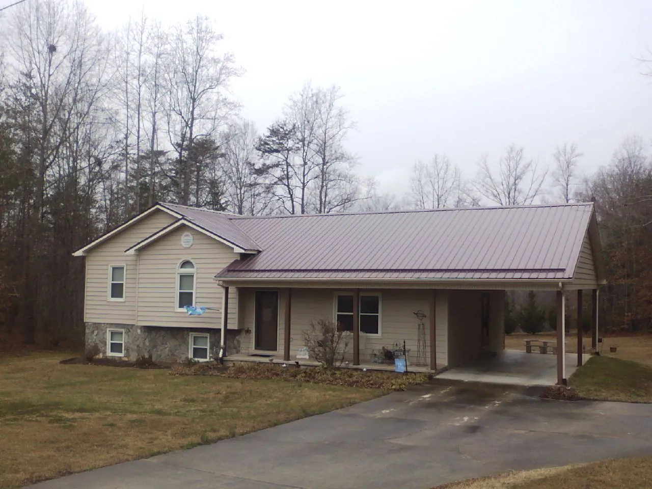 Burgundy metal roof on a tan split level home with an attached carport in Highland Park