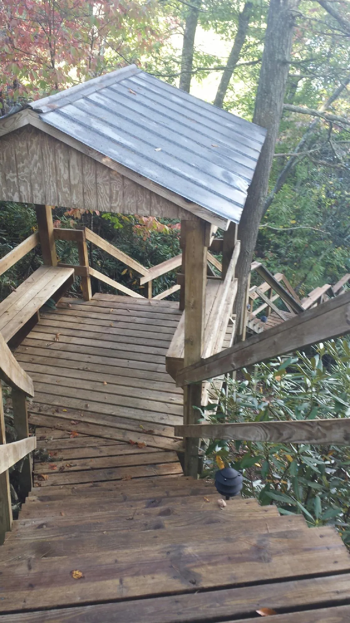 Metal roofed shelter over wooden steps on a wooded walkway — Skylight Repair & Installation work by our crew in Highland Park