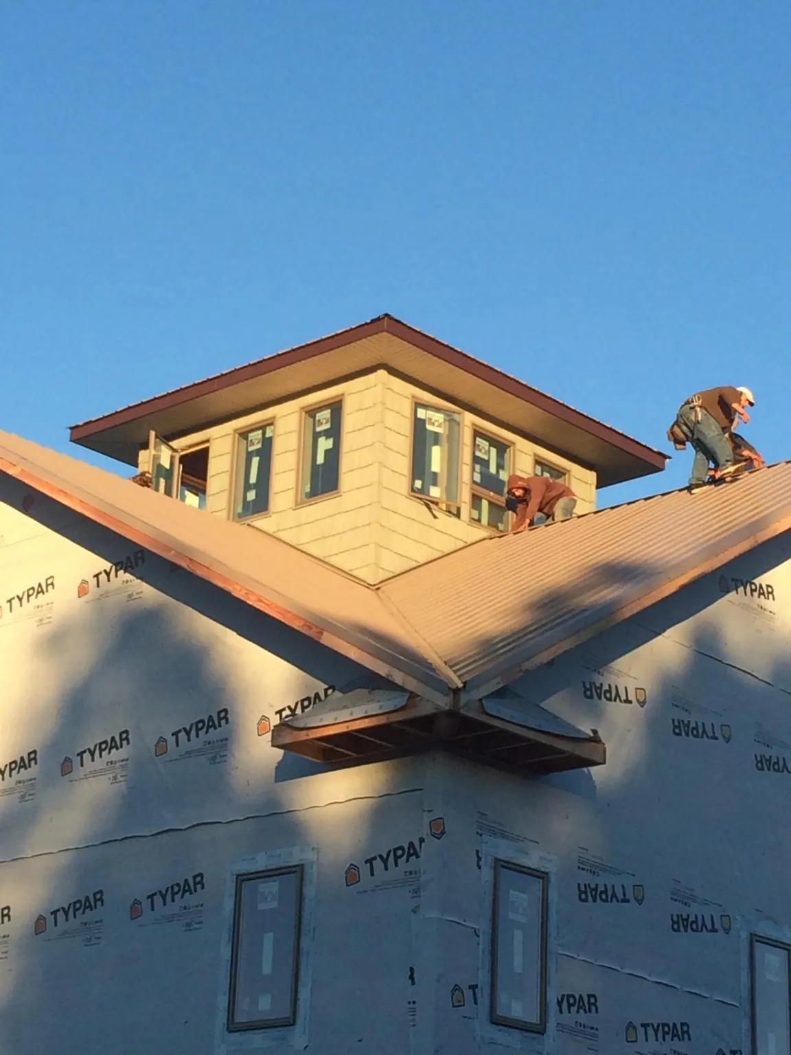 Roofers working around a rooftop cupola on a new metal roof at sunset — Roof Waterproofing in Highland Park by Roofing Brothers